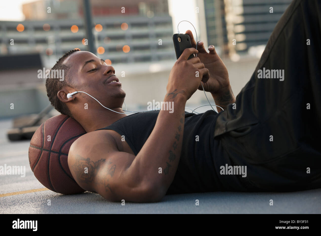USA, Utah, Salt Lake City, junge Mann liegend auf Basketball und anhören von MP3-player Stockfoto