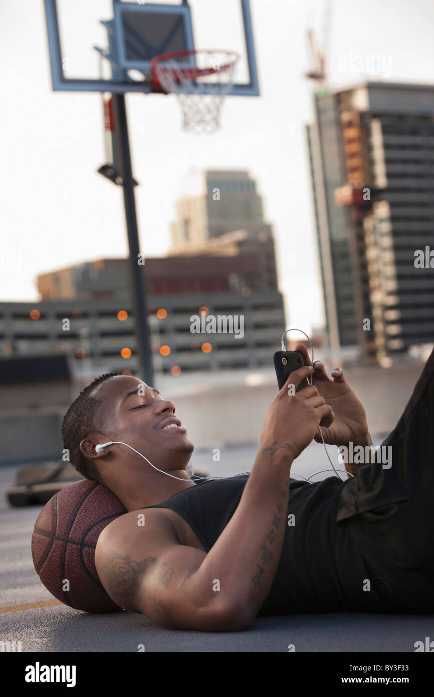 USA, Utah, Salt Lake City, junge Mann liegend auf Basketball und anhören von MP3-player Stockfoto