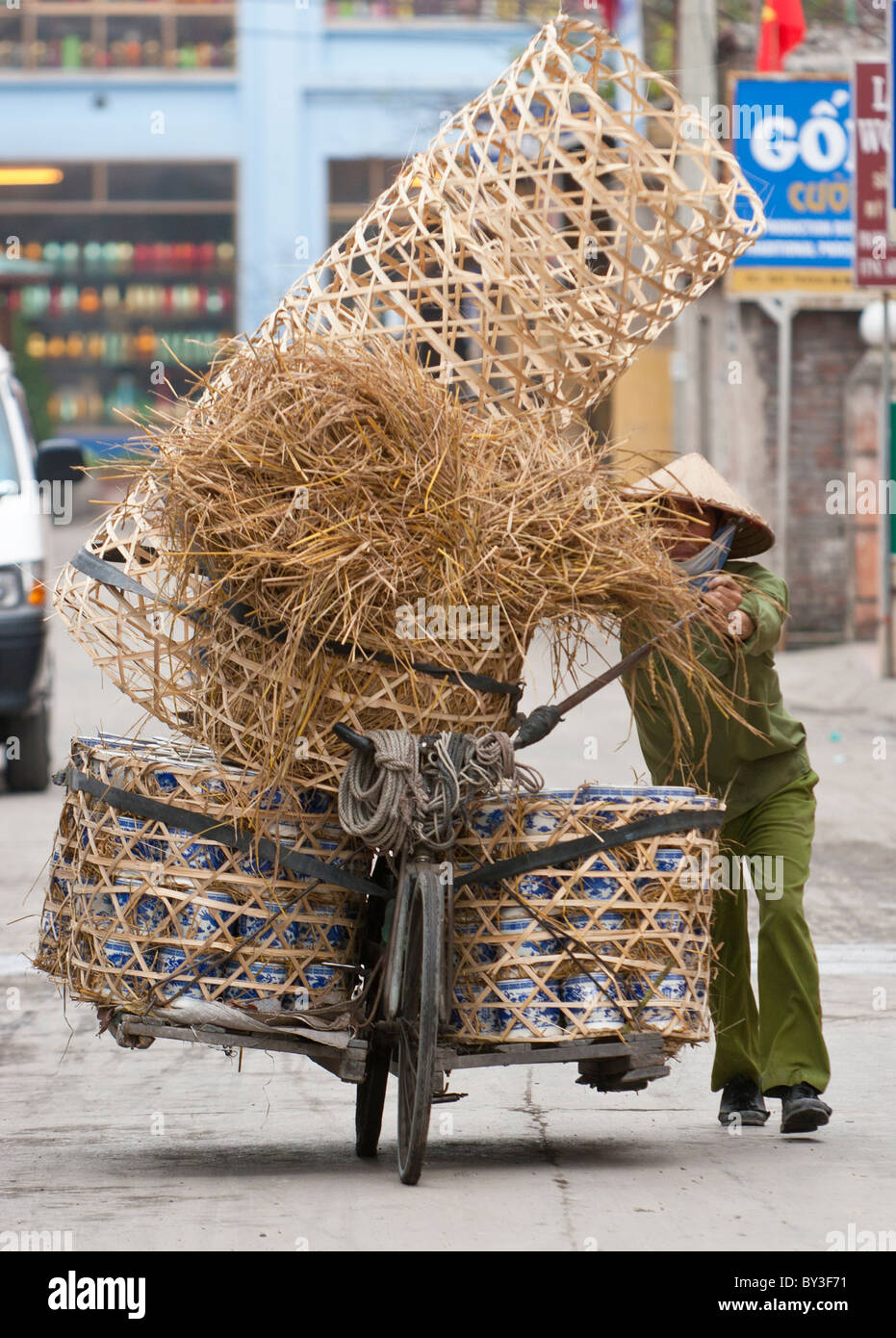 Frau in grüne Kleidung und traditionelle konische Hut schieben eine