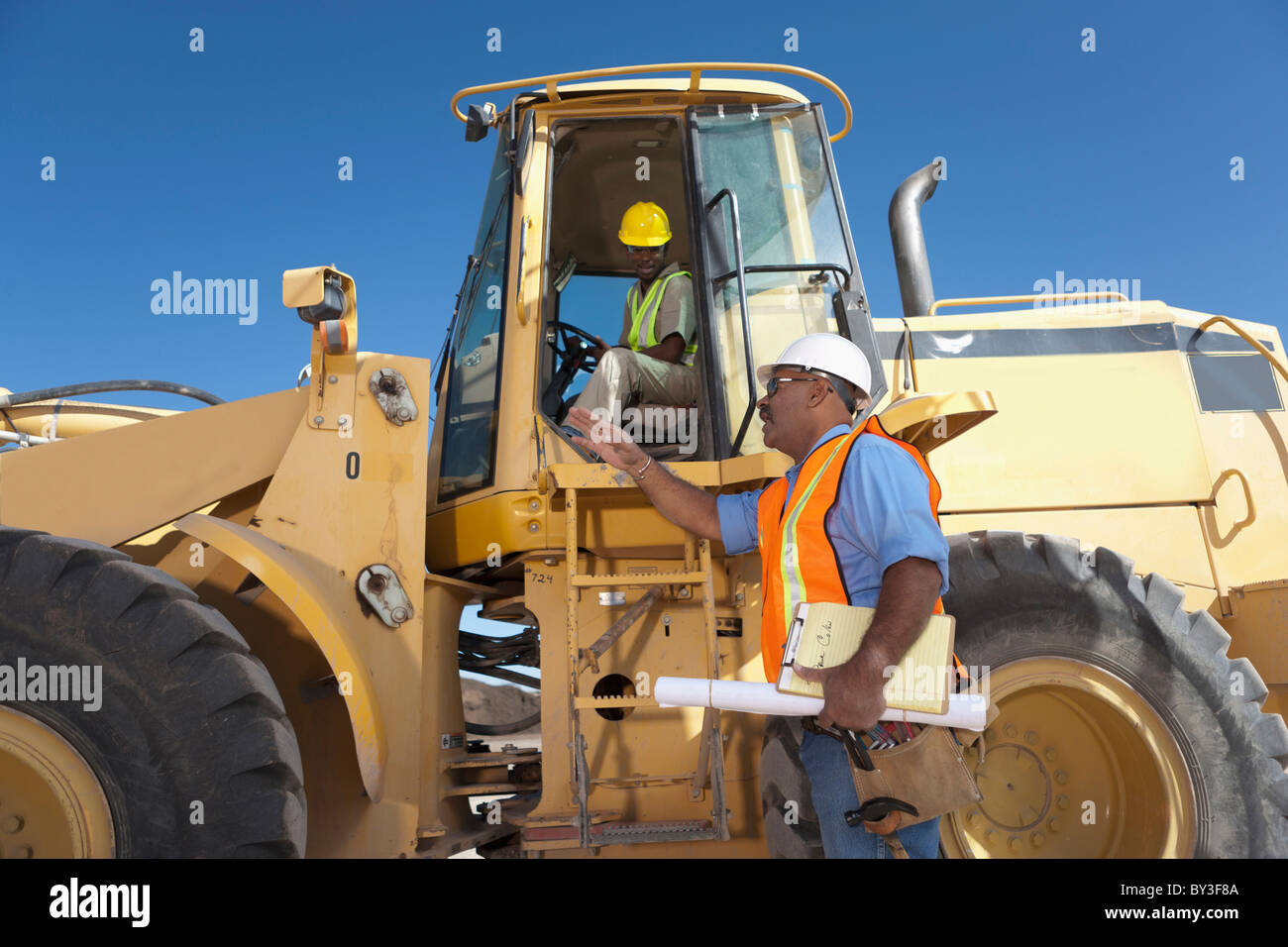 Zwei Bauarbeiter sprechen von mechanischen digger Stockfoto