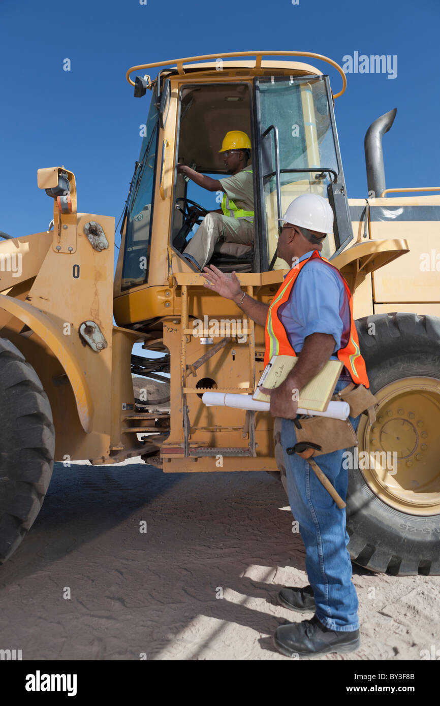 Zwei Bauarbeiter sprechen von mechanischen digger Stockfoto
