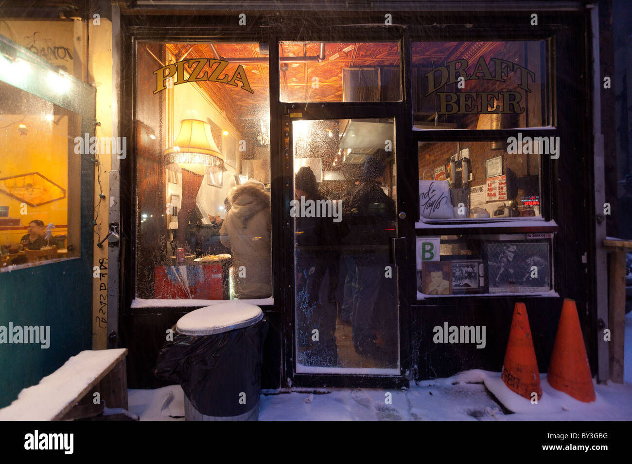 Kunden verpackt in Artichoke Basille Pizza in New York City in Winternacht während der rauen Schneesturm in Weihnachten 2010 Stockfoto