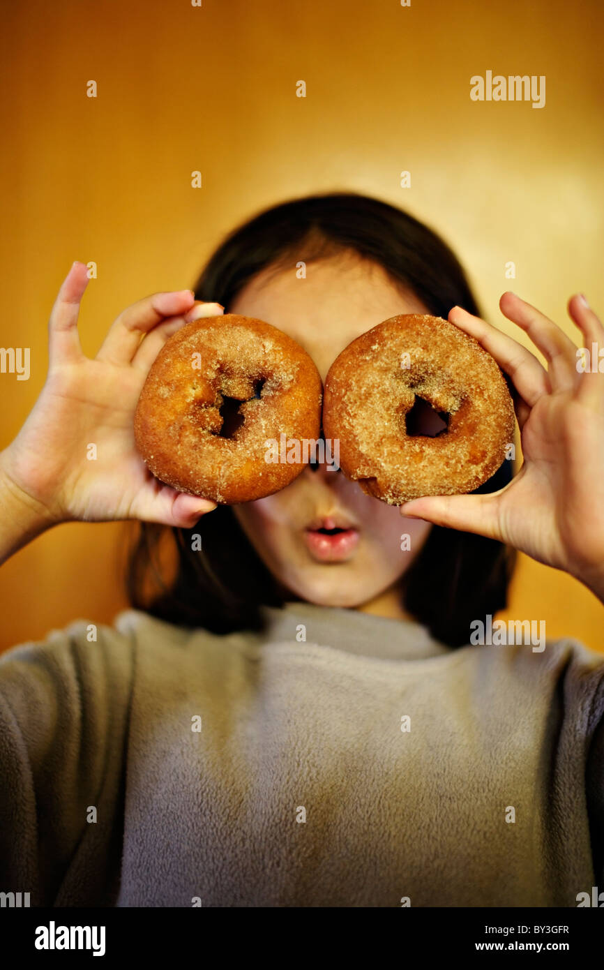 Mädchen halten Donuts über Augen. Stockfoto