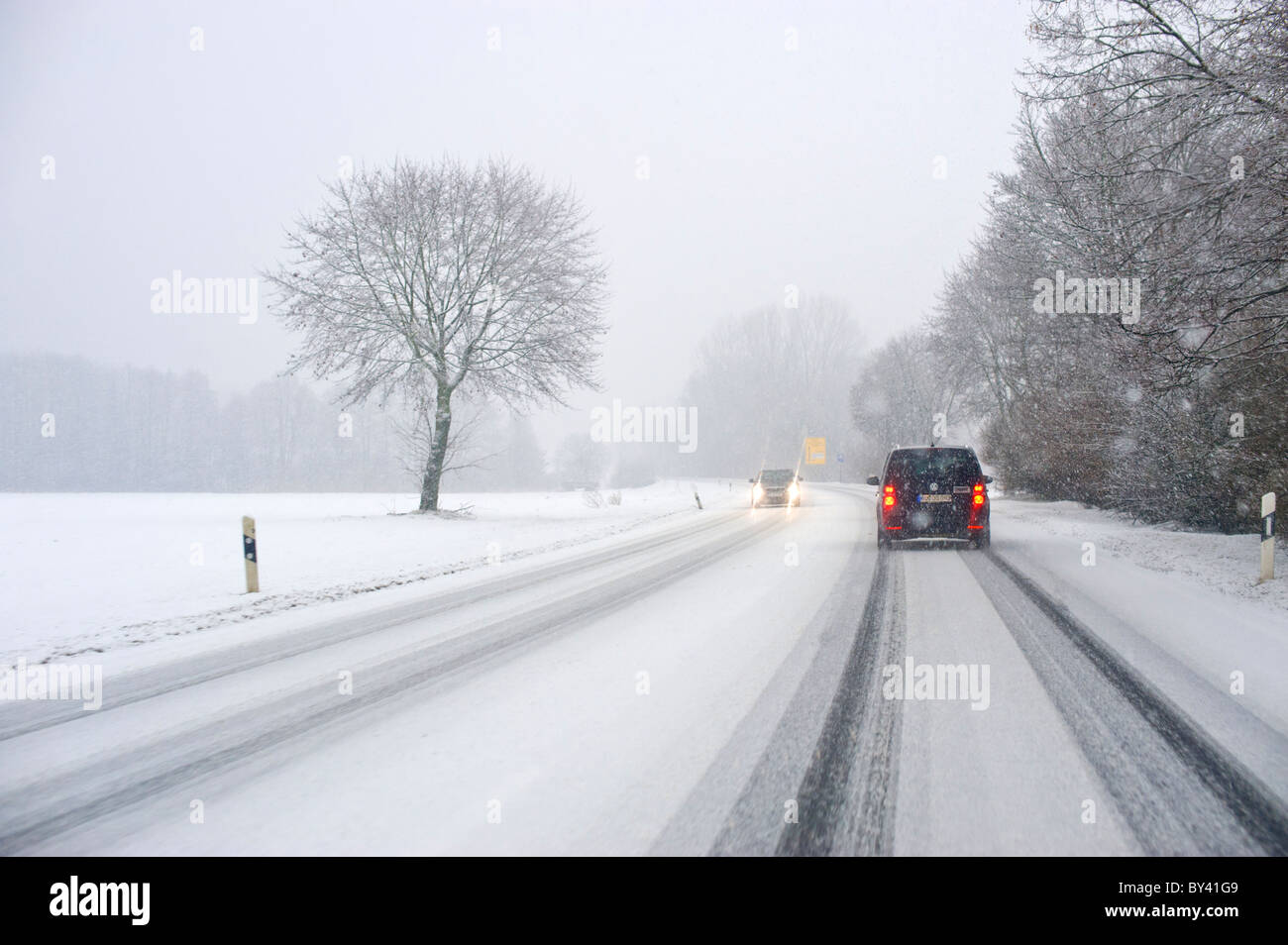 Straßenverhältnisse Winter Winter Straße gesehen aus einem Auto Fenster Carwindow Schnee schneit eisigen überdachte Straße Straße Eisdecke Stockfoto