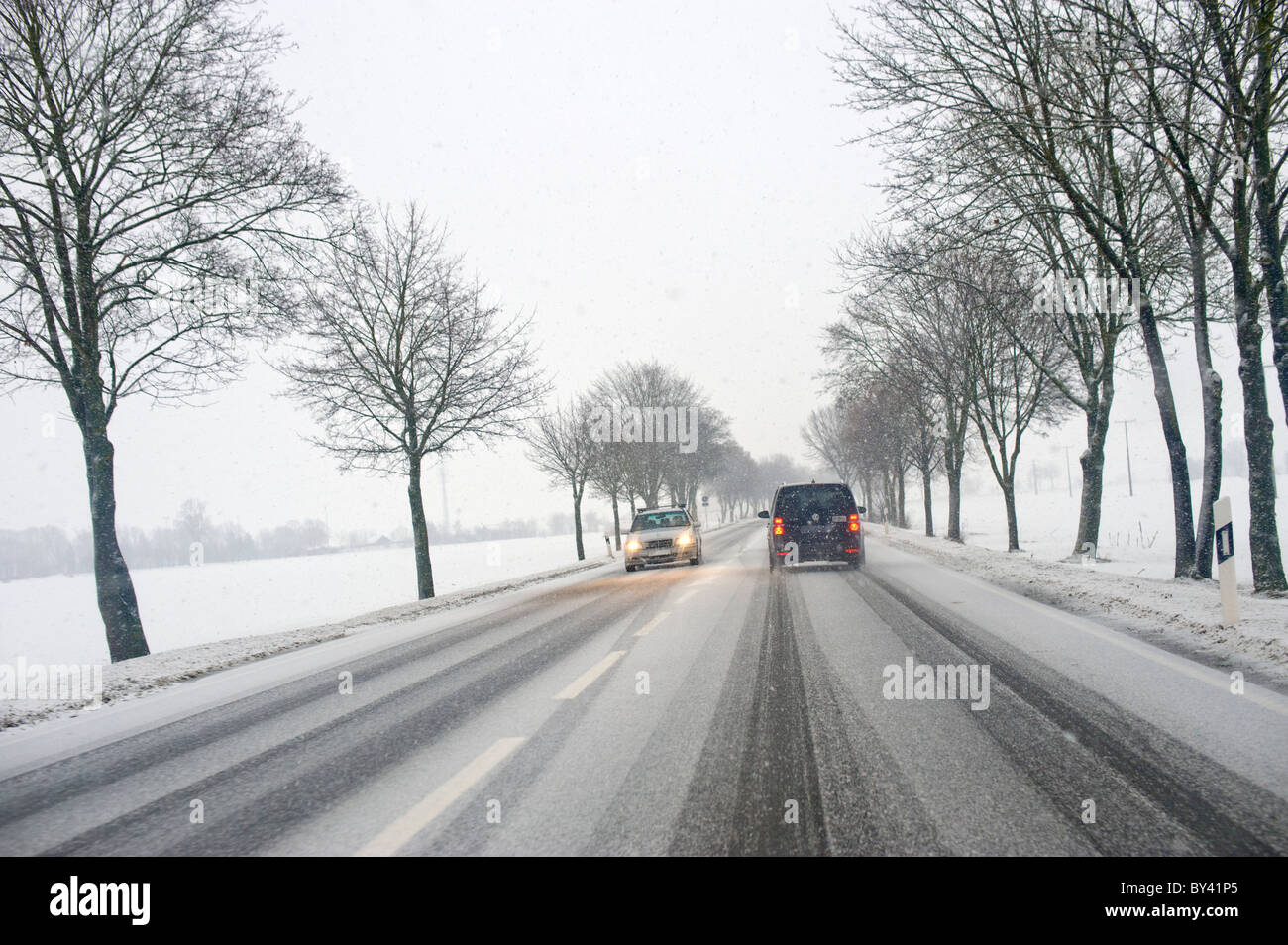 Straßenverhältnisse Winter Winter Straße gesehen aus einem Auto Fenster Carwindow Schnee schneit eisigen überdachte Straße Straße Eisdecke Stockfoto