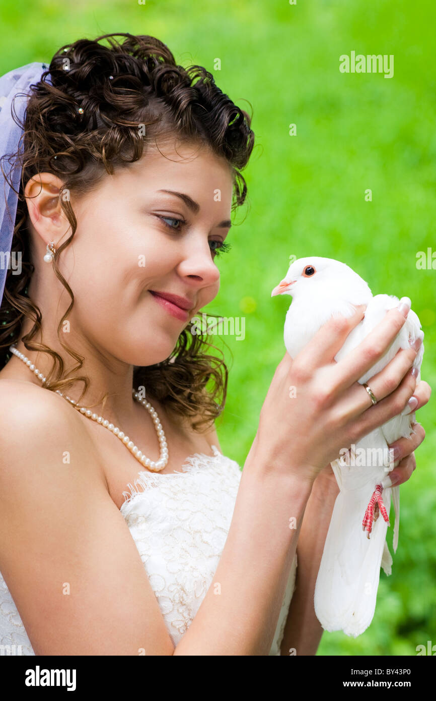 Foto der schönen Braut hält weiße Taube Hände und betrachten sie mit Lächeln Stockfoto