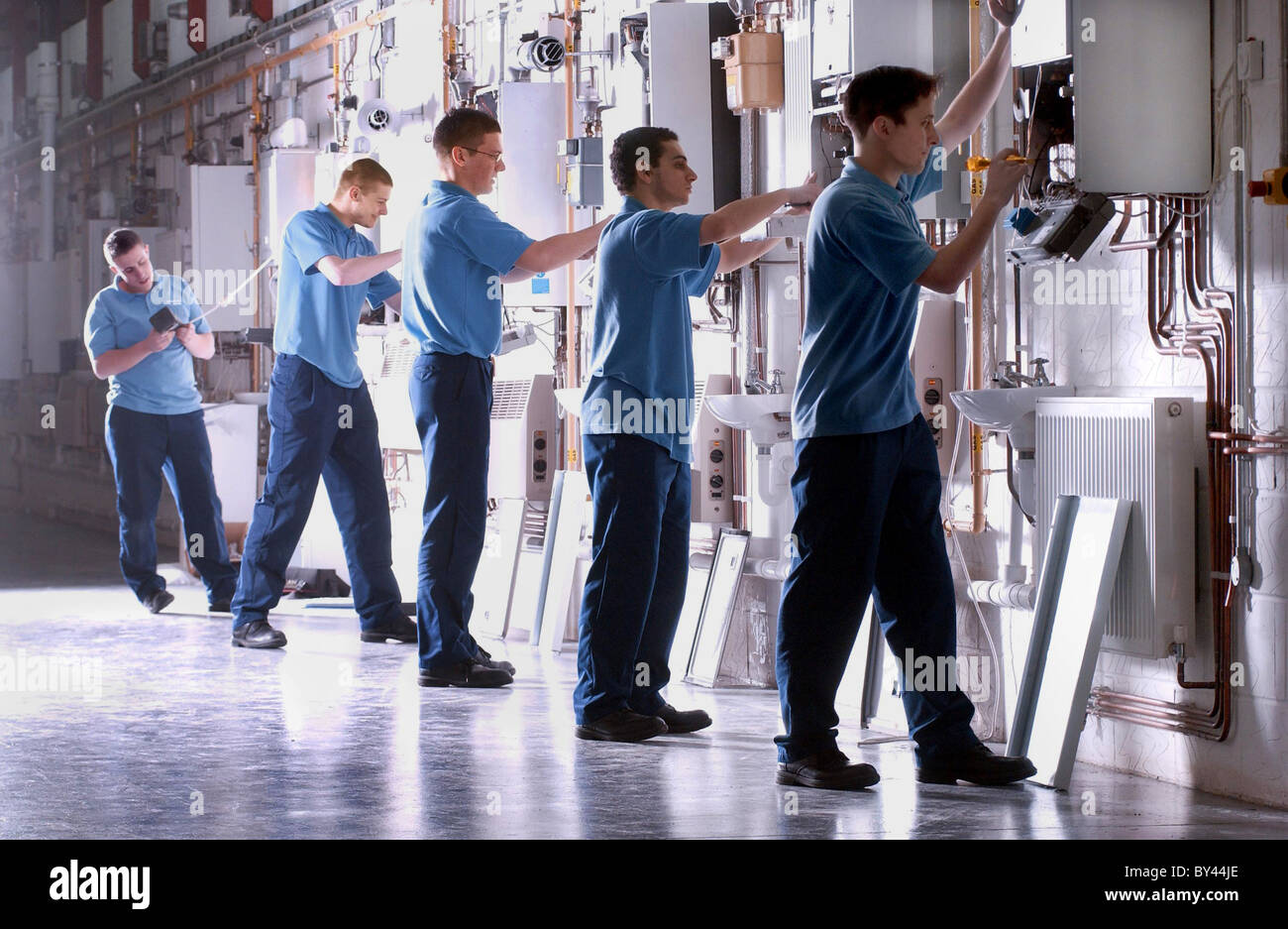 Lernen am Arbeitsplatz Lehrling Gas Installateure passen Kessel in Sanitär-Klasse Stockfoto