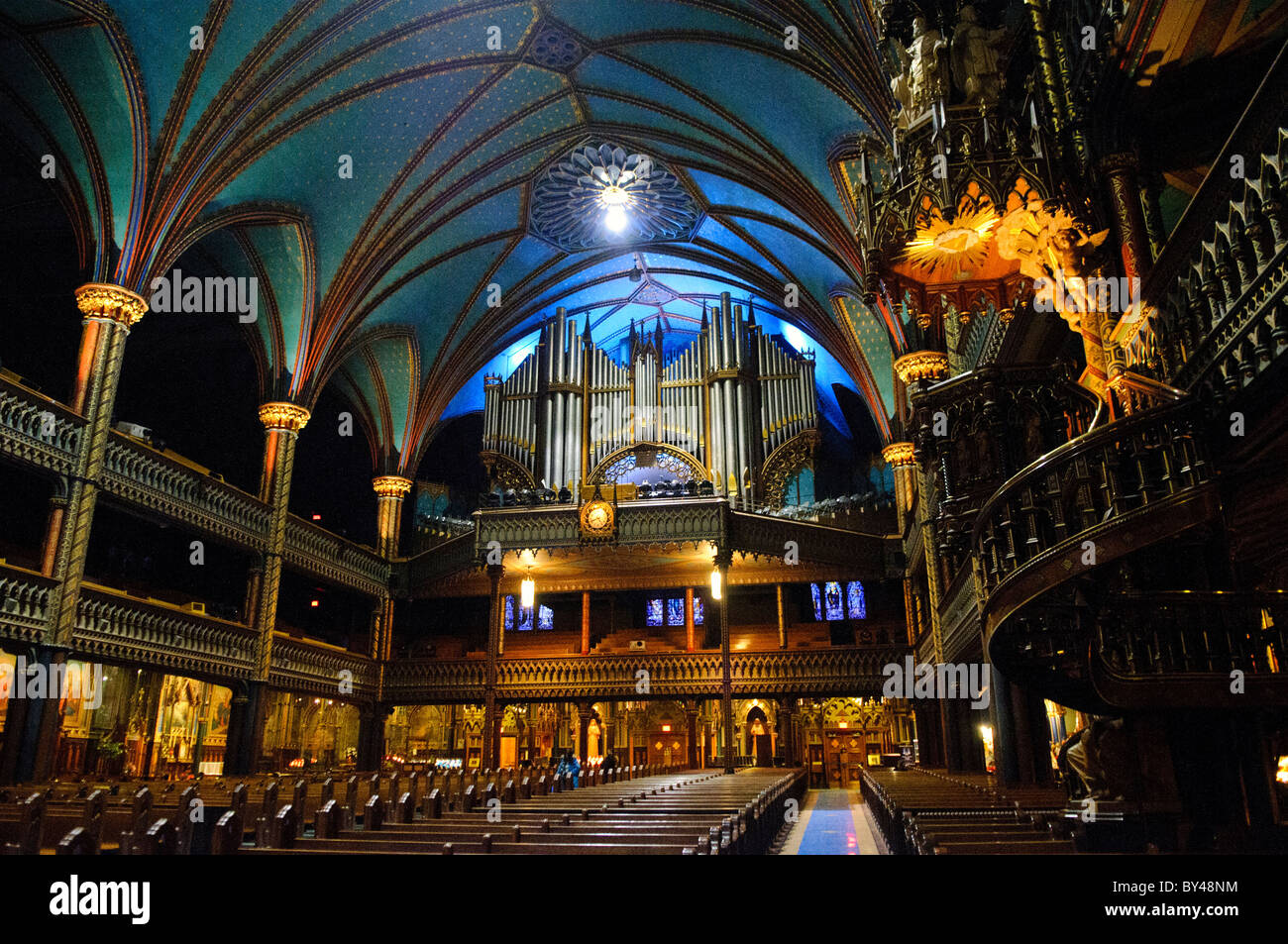 Notre-Dame Basilica Pipe Orgel Montreal Canada // MONTREAL, Kanada — der Blick auf den Eingang der Basilika Notre-Dame zeigt die monumentale Pfeifenorgel Casavant Frères aus dem Jahr 1891 mit 9.000 Pfeifen und vier Tastaturen. Die Basilika war nach ihrer Fertigstellung in den 1840er Jahren die größte Kirche Nordamerikas. Das Innere der Basilika besticht durch außergewöhnliche, im gotischen Stil erbaute Architektur und dramatische Beleuchtung. Dieser Blick vom Heiligtum hebt die Pracht des Hauptschiffs der historischen Kirche hervor. Stockfoto