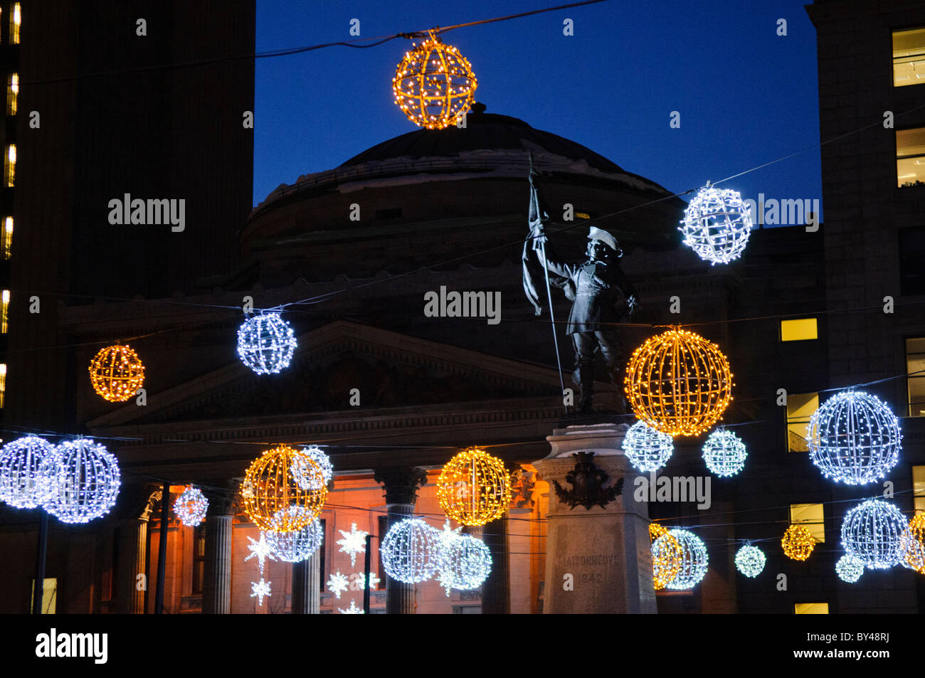 MONTREAL, Kanada – während der Wintersaison erleuchten die Lichter des Platzes Place d'Armes vor der historischen Basilika Notre-Dame. Der historische Platz aus der Kolonialzeit von Montreal bildet einen dramatischen Vorsprung zur neugotischen Basilika. Diese festliche Ausstellung im historischen Viertel von Old Montreal schafft eine der meistfotografierten Winterszenen der Stadt. Stockfoto