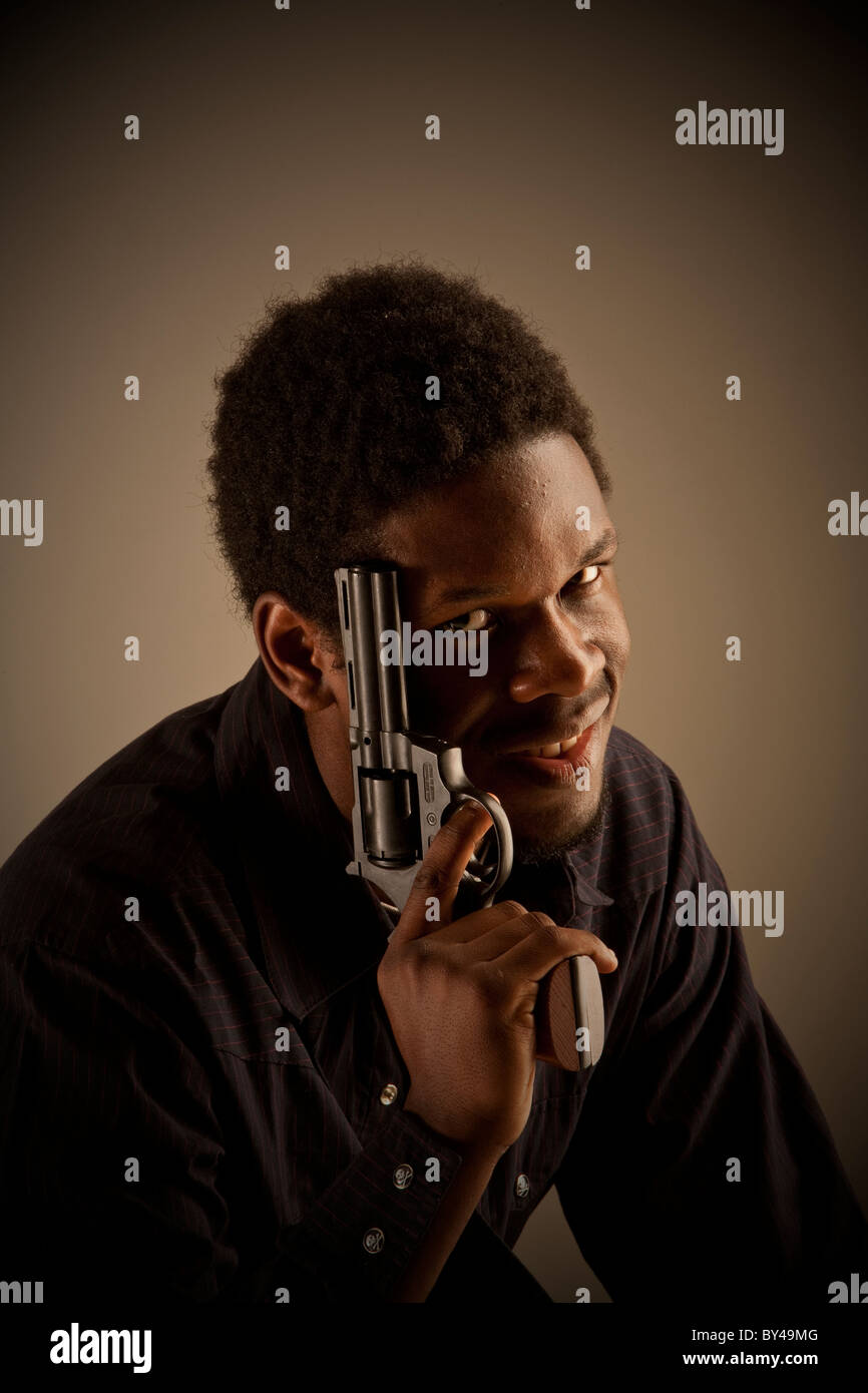 Junge schwarze männliche Model posiert mit einer Pistole Stockfoto