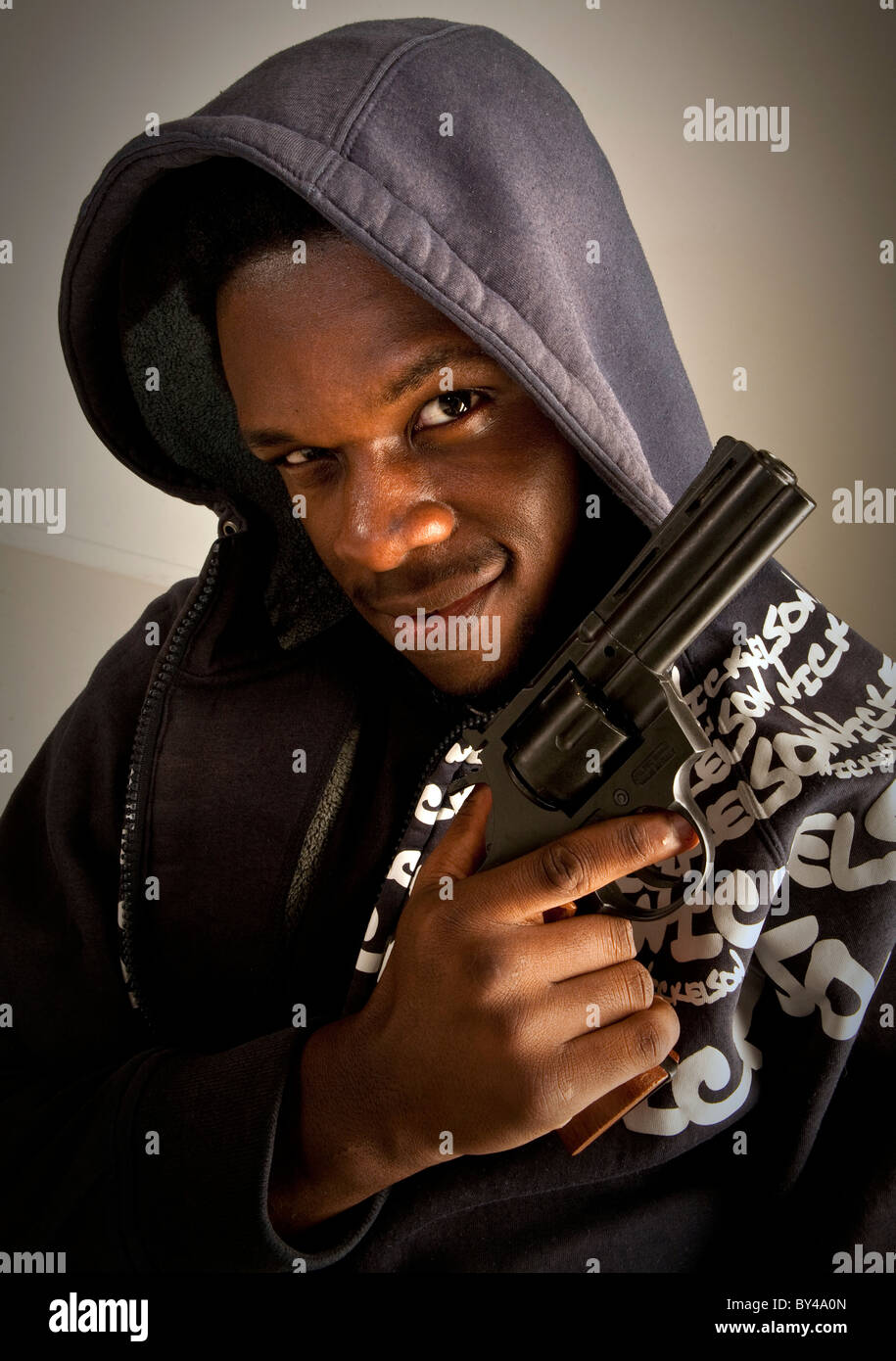 Junge schwarze männliche Model posiert mit einer Pistole Stockfoto