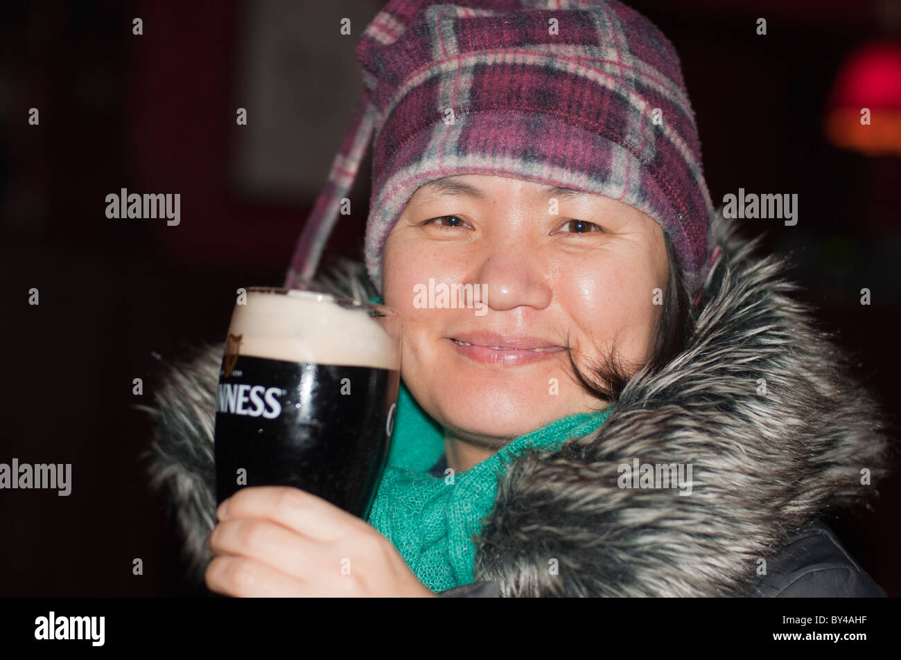 Eine asiatische Frau trinkt einen Pint Guinness in einem irischen Pub in Limerick, Irland. Stockfoto