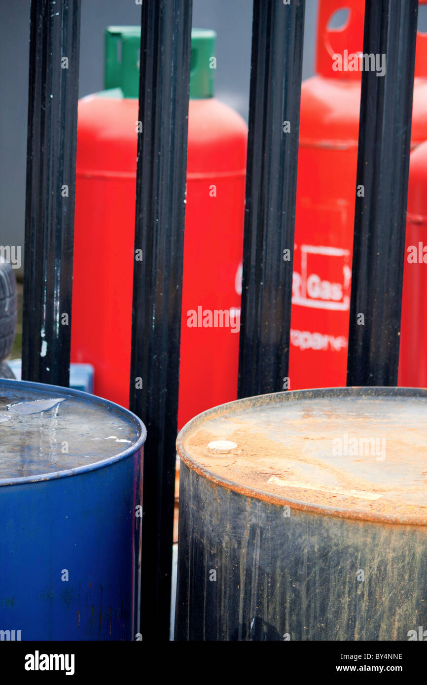 Zwei flüssigen chemischen Ölfässer für Giftmüll vor einem Stahl Zaun und Calor Gas Flaschen Stockfoto