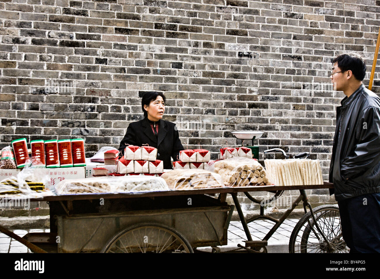 CHINA, XIAN: Chinesin verkauft eine Vielzahl von Nudeln und Tofu aus ihrem Fahrrad Warenkorb im muslimischen Viertel der alten Xian, China. Stockfoto