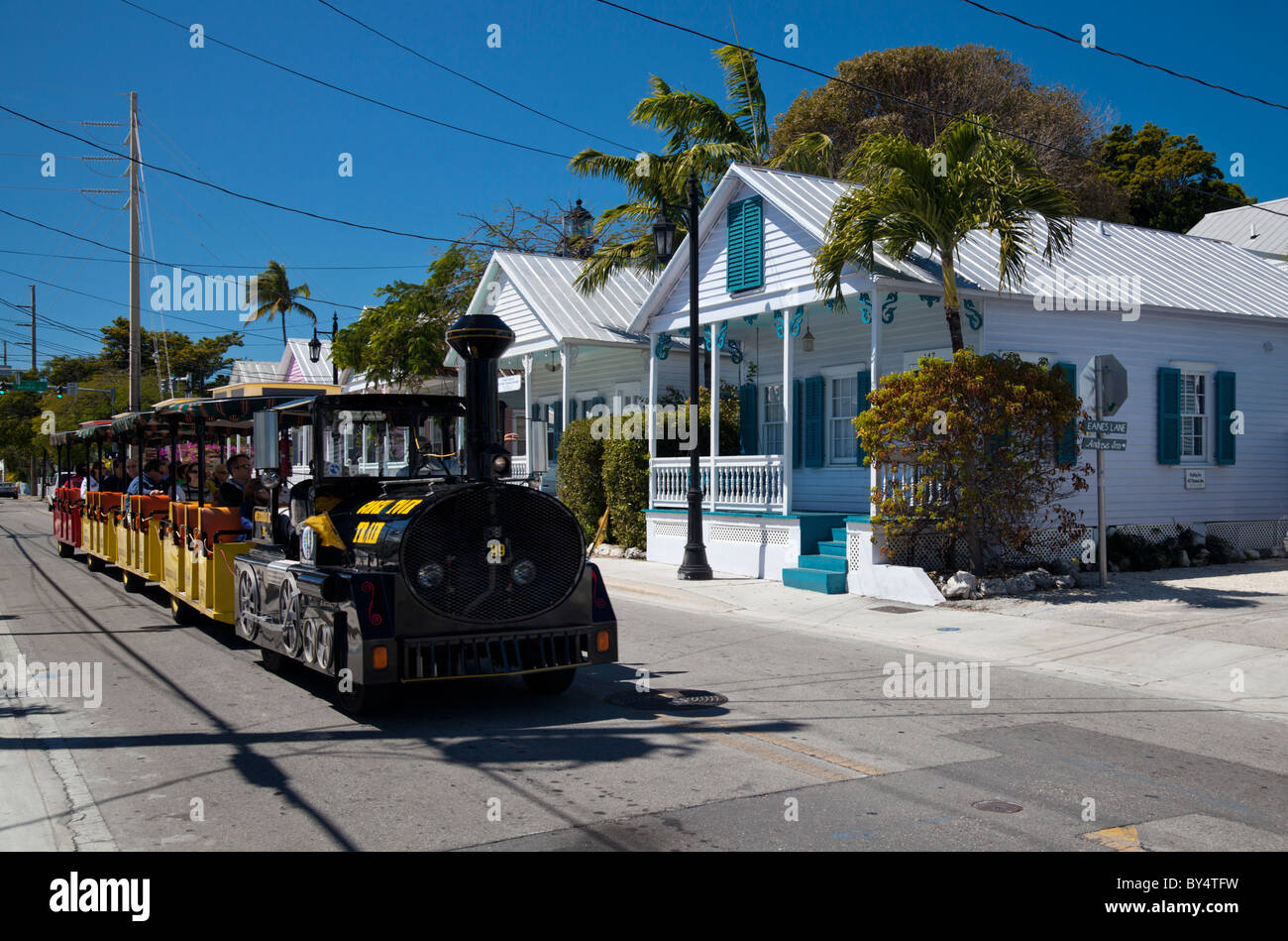 Der Conch Tour Zug geht eine Reihe von hübschen kleinen Hütte Stil Häuser in Key West, Florida, USA Stockfoto