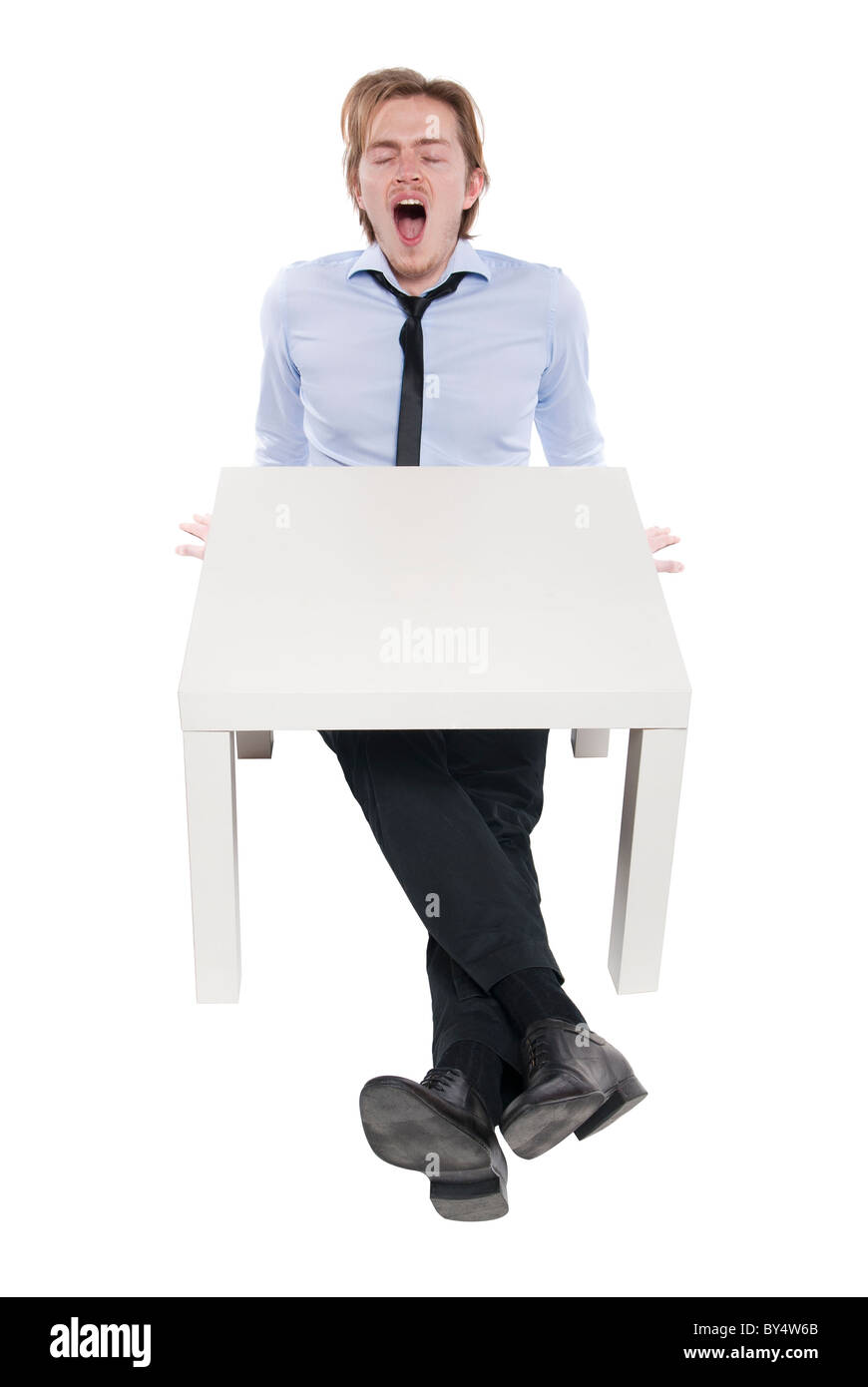 Junger Geschäftsmann, Büroangestellter oder Student an lustigen kleinen Tisch sitzen. Studio Foto, isoliert. Stockfoto