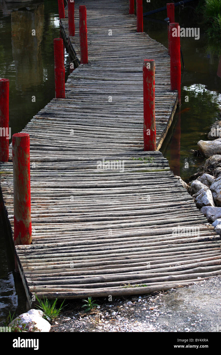 Eine wacklige Holzbrücke über einen großen Teich oder See voller Wasser Stockfoto