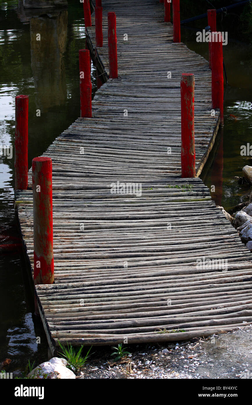 Eine wacklige Holzbrücke über einen großen Teich oder See voller Wasser Stockfoto