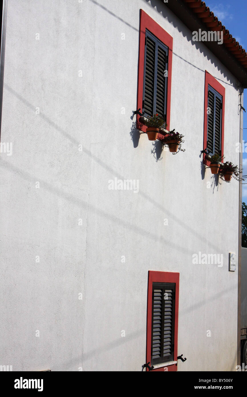 Der Seite ein weißes Gebäude in Portugal; zeigt das Fenster, Fensterläden, Blumenkästen und Schatten Stockfoto