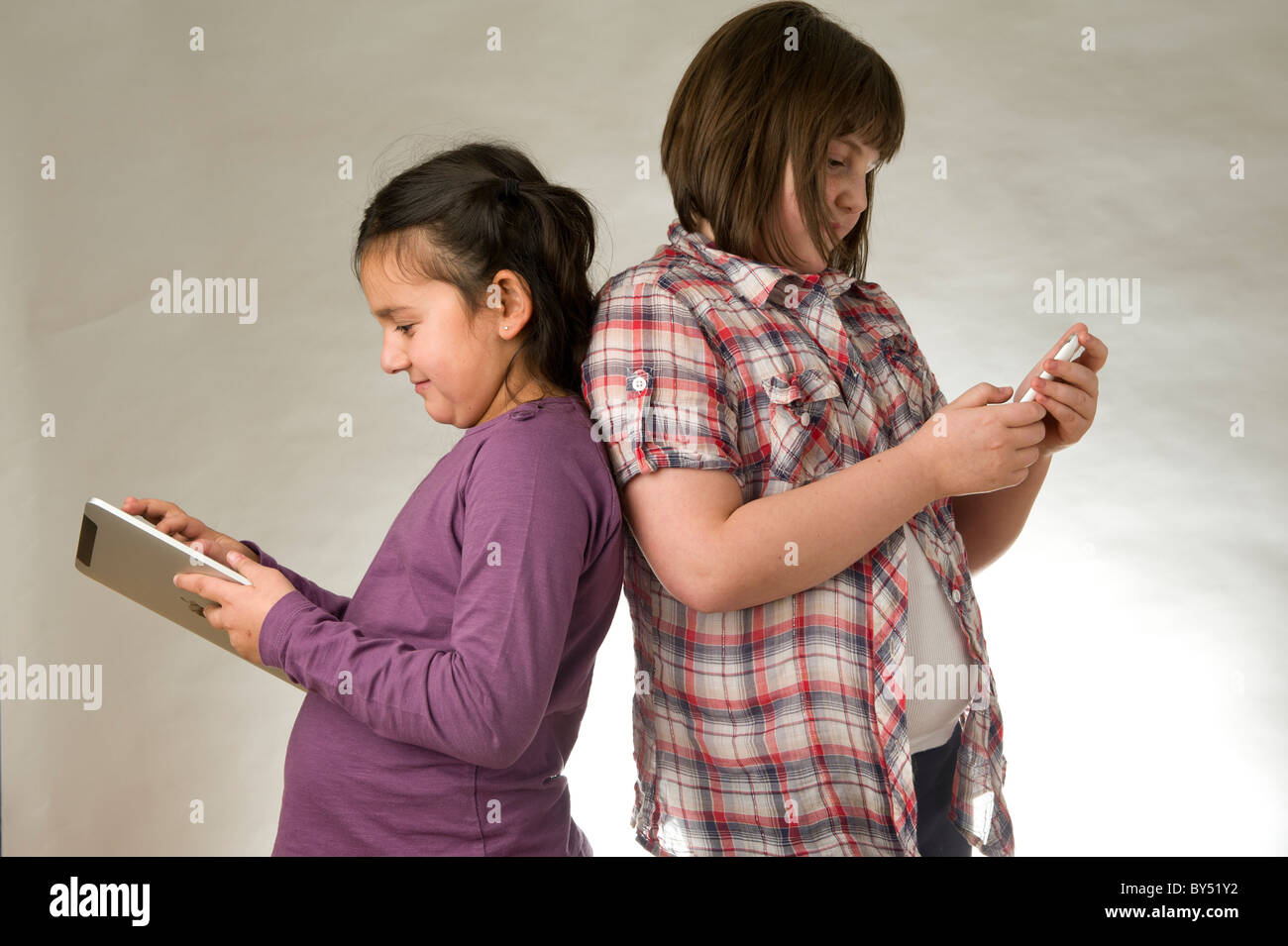 Zwei junge Mädchen spielen elektronischer Spiele auf einem Touchscreen pad Stockfoto