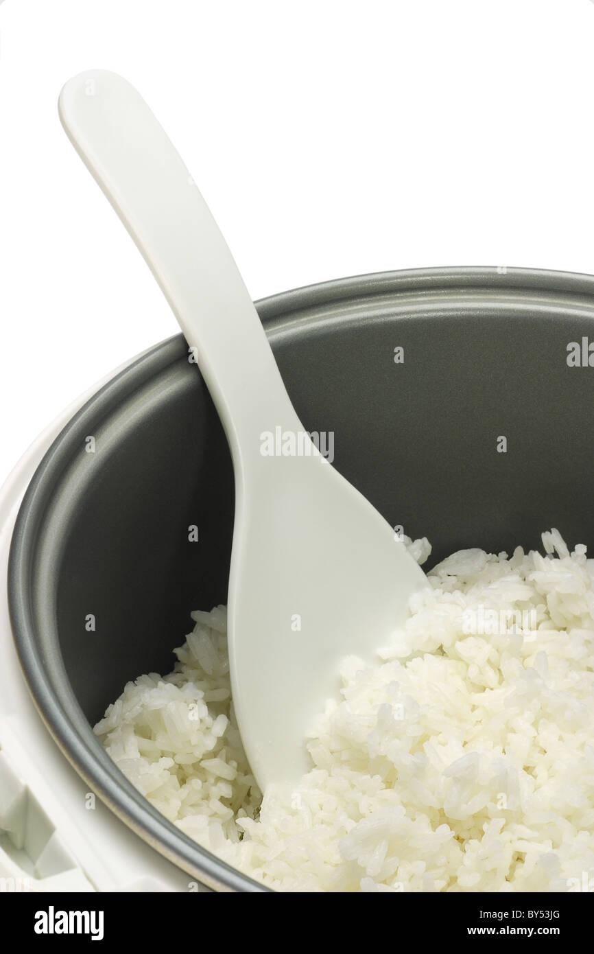 Gekochter Reis im Reiskocher Topf mit Plastiklöffel auf weißem Hintergrund Stockfoto