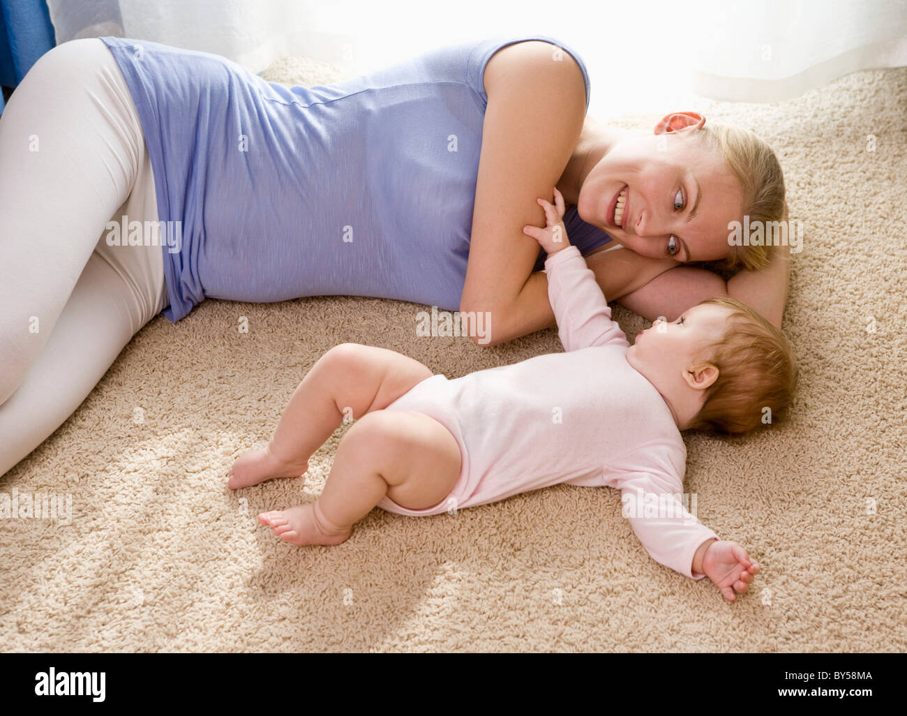 Eine Mutter und ihr Baby liegend auf einem Teppichboden Stockfoto