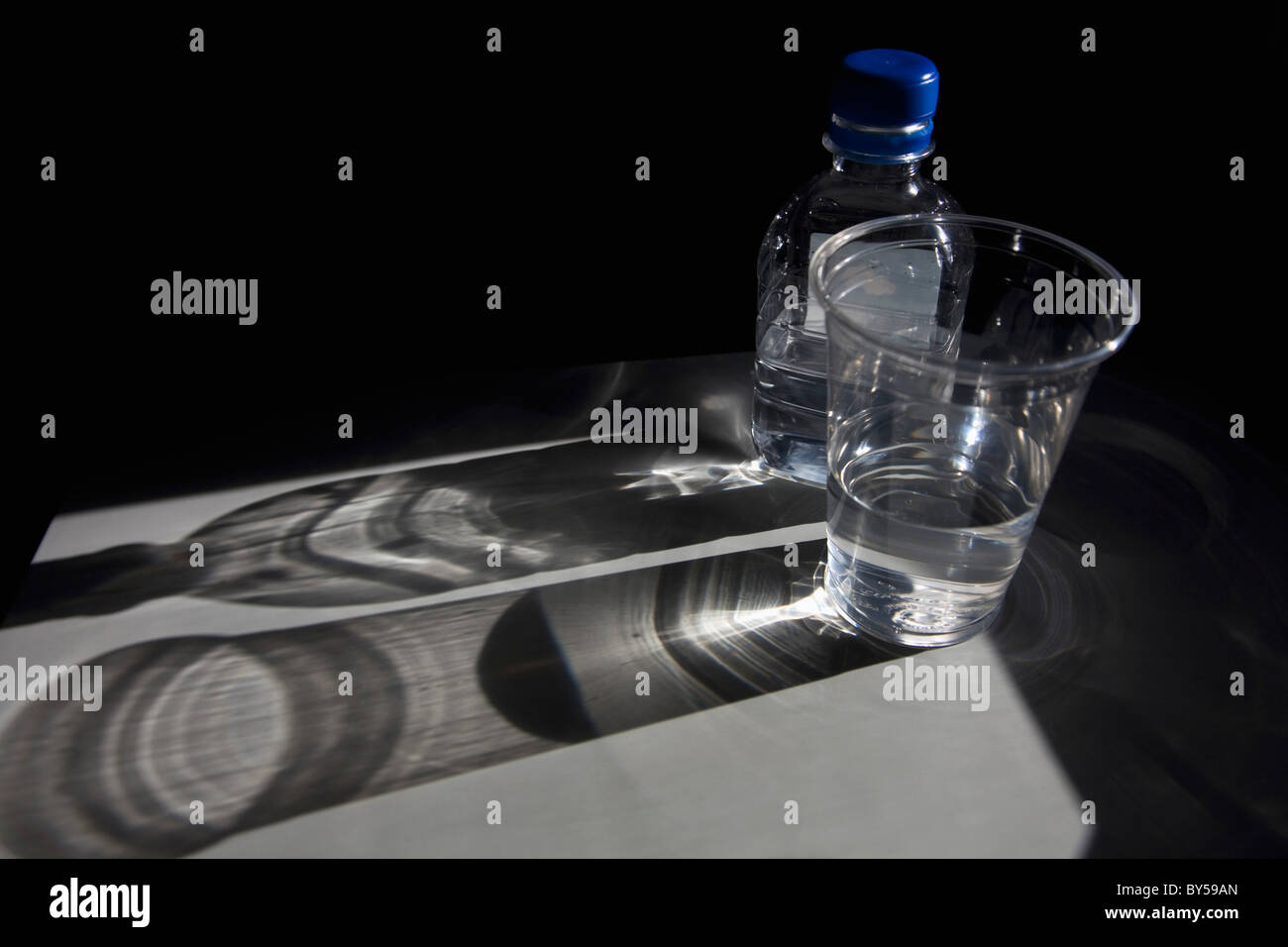 Ein Kunststoff-Flasche und eine Tasse Wasser auf einem Tisch Stockfoto