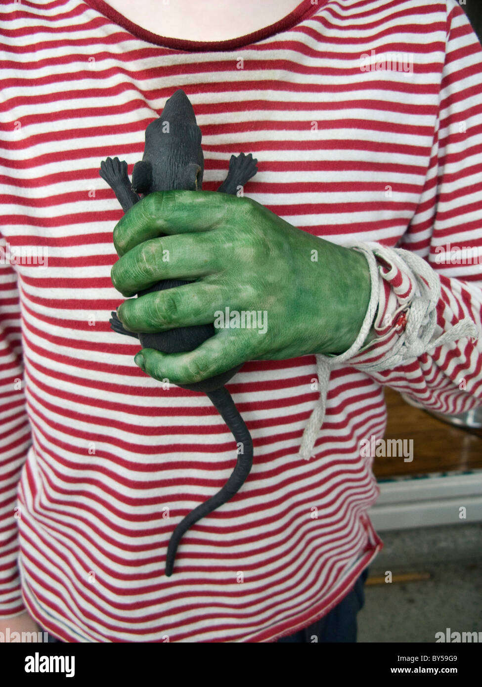 Eine Person mit einer grünen Hand hält eine Spielzeug-Ratte Stockfoto