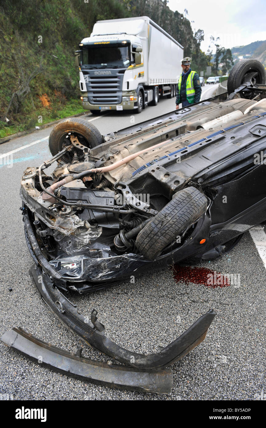 Ein LKW geht von einem zerstörten und umgestürzten Auto IP3 unterwegs in Zentral-Portugal nach einem Autounfall Stockfoto
