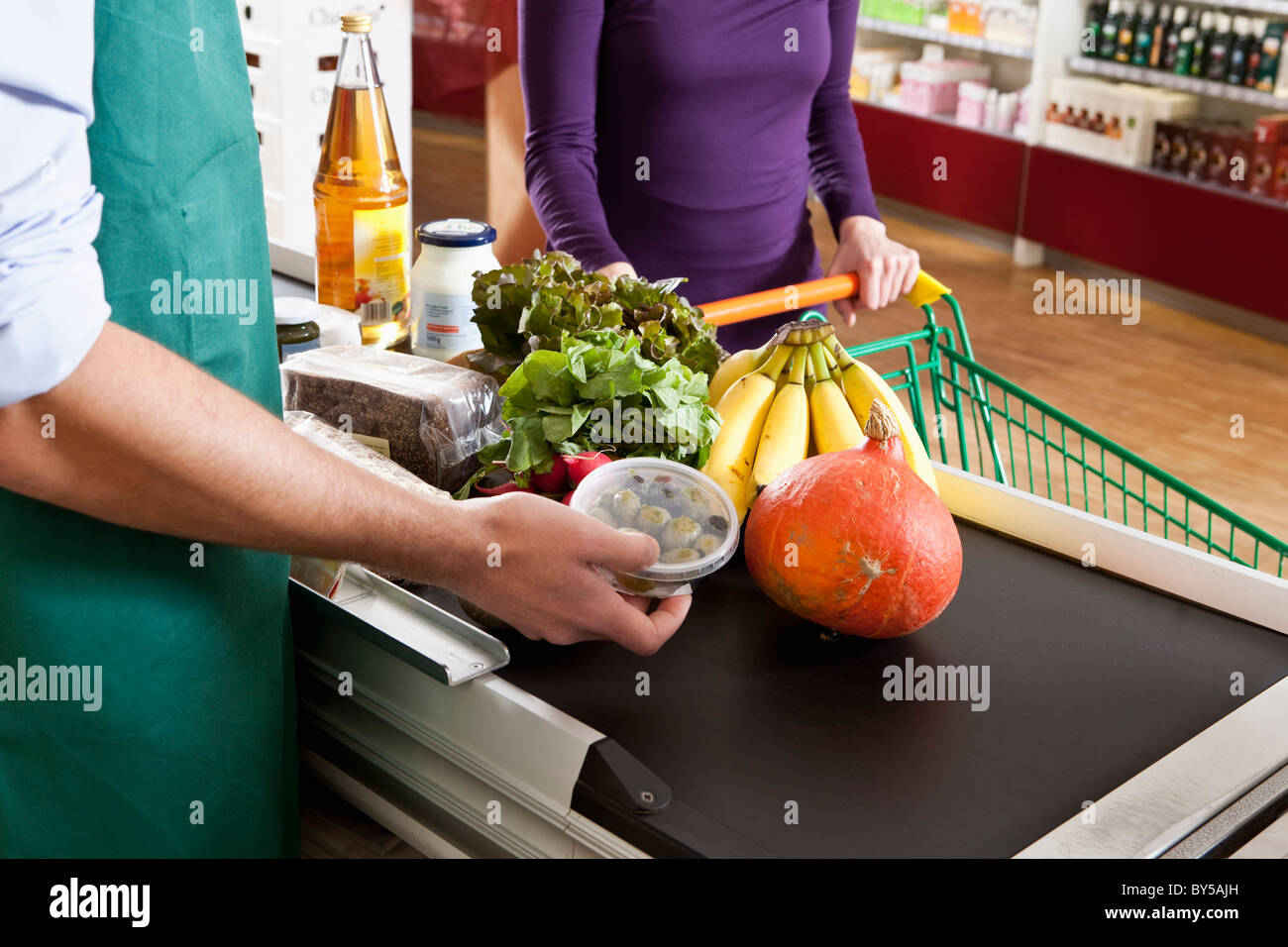 Ein Kassierer und Kunden an der Kasse eines Supermarktes, Mittelteil Stockfoto