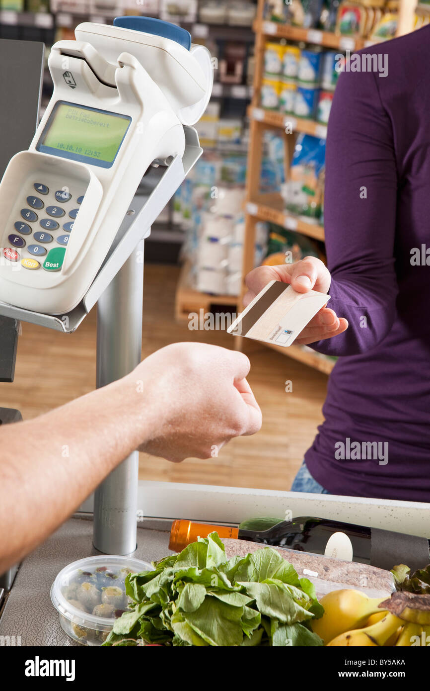 Ein Kunde übergibt einer Kassiererin eine Kreditkarte im Supermarkt Stockfoto
