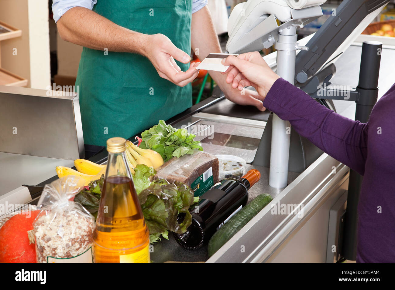 Ein Kunde übergibt einer Kassiererin eine Kreditkarte im Supermarkt Stockfoto