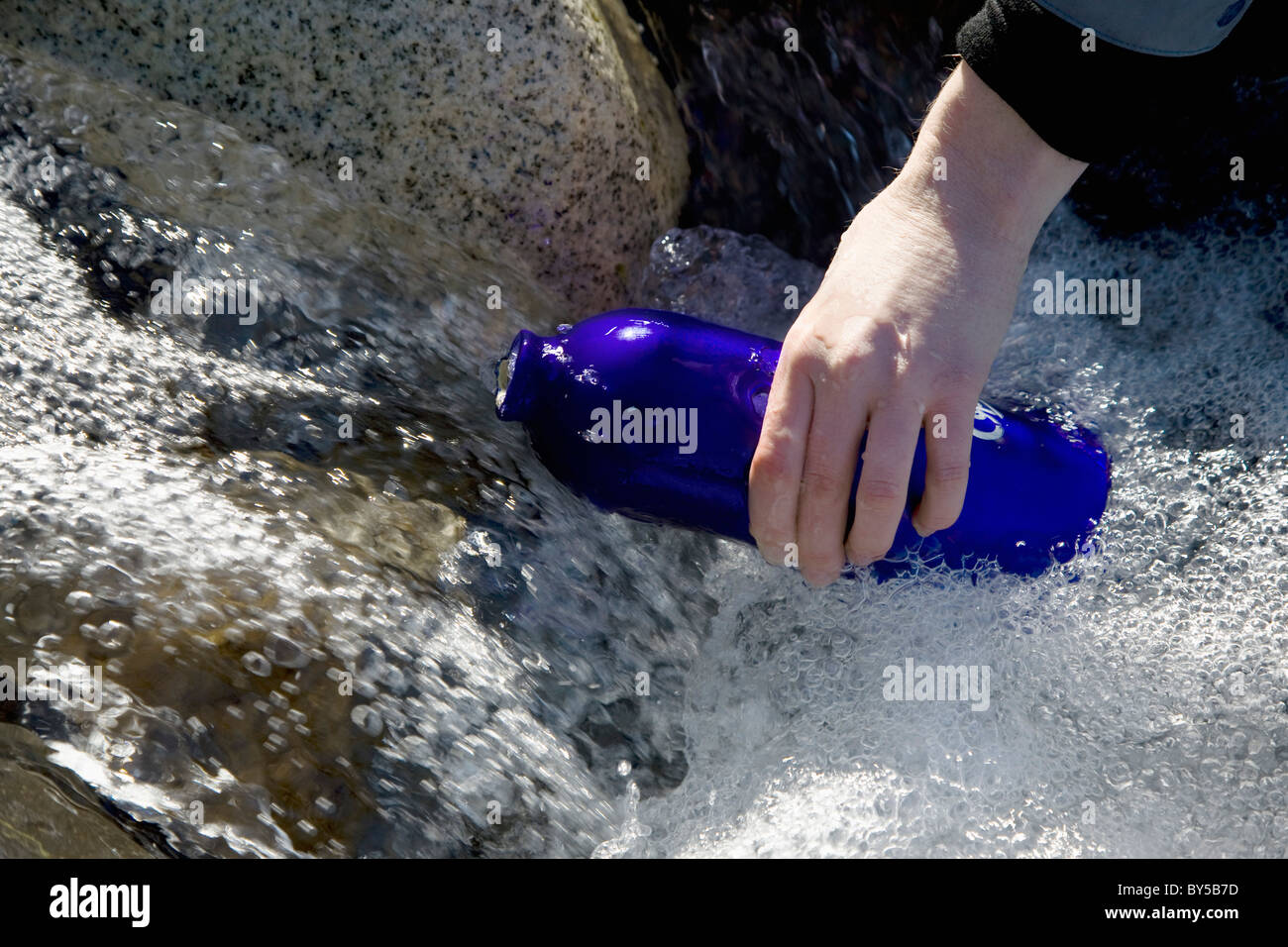 Detail einer Person füllt eine Trinkflasche in einem Fluss Stockfoto