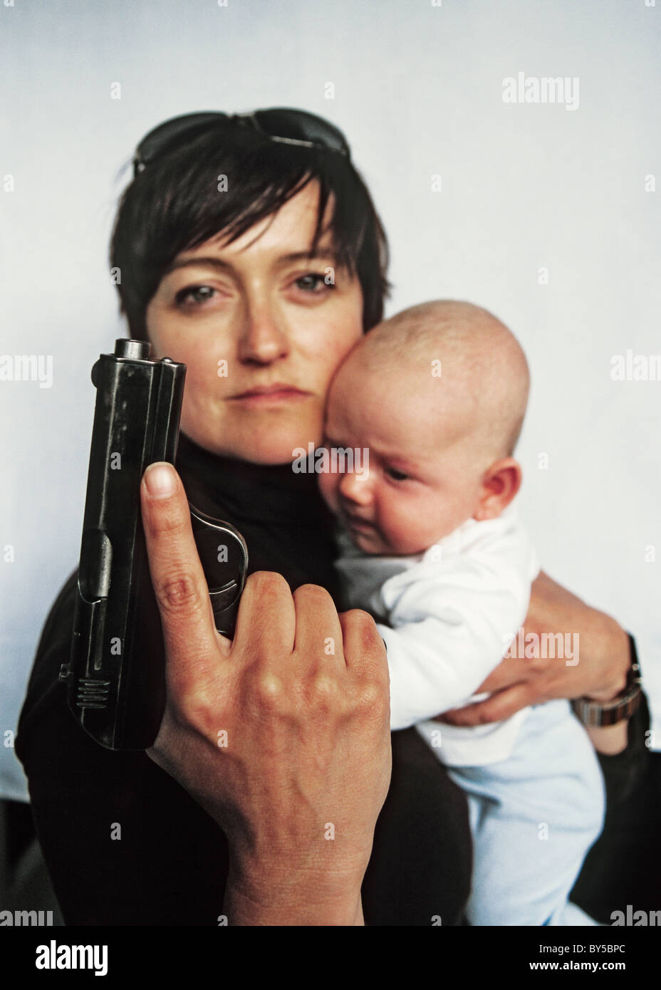Eine Mutter hält eine Pistole und ein Baby in ihrem arm Stockfoto