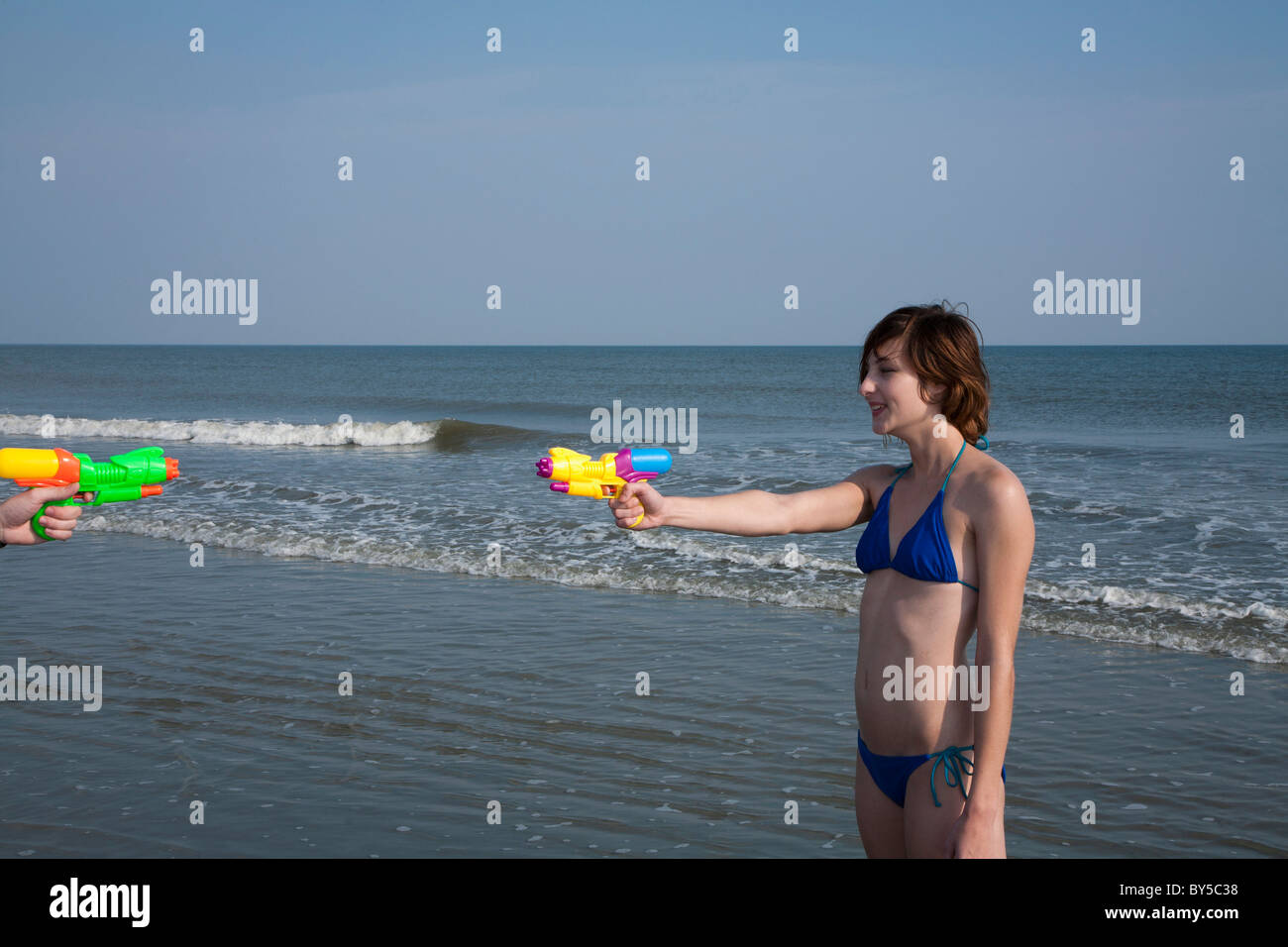 Freunde mit Spritzpistolen spielen am Strand Stockfoto