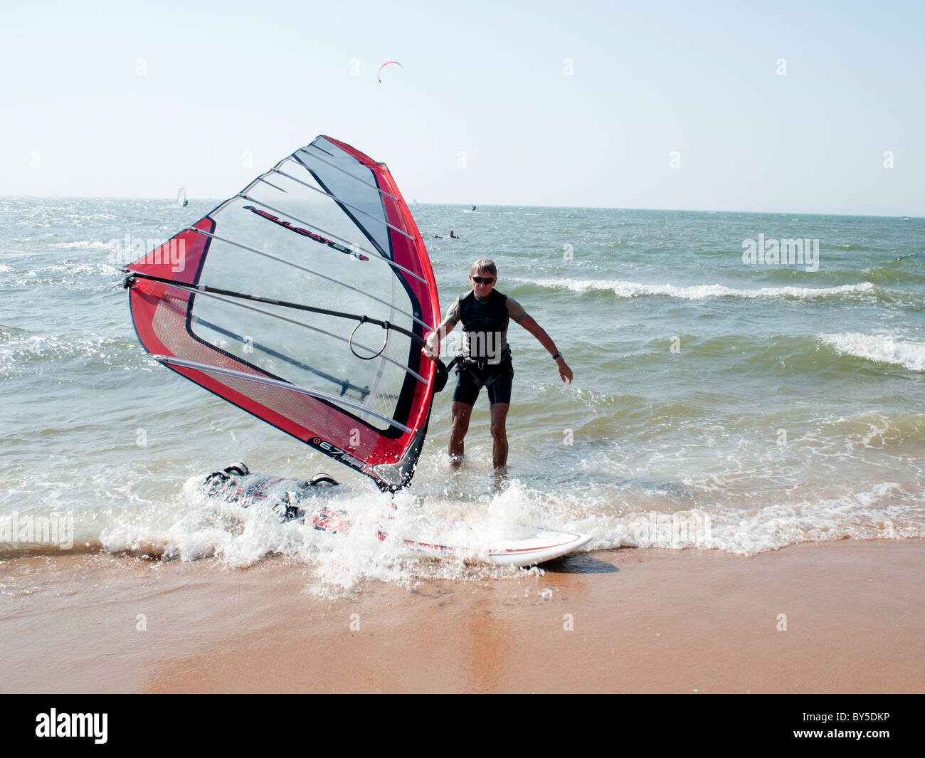 Ein senior Windsurfer kommen an den Strand nach Segeln Stockfoto