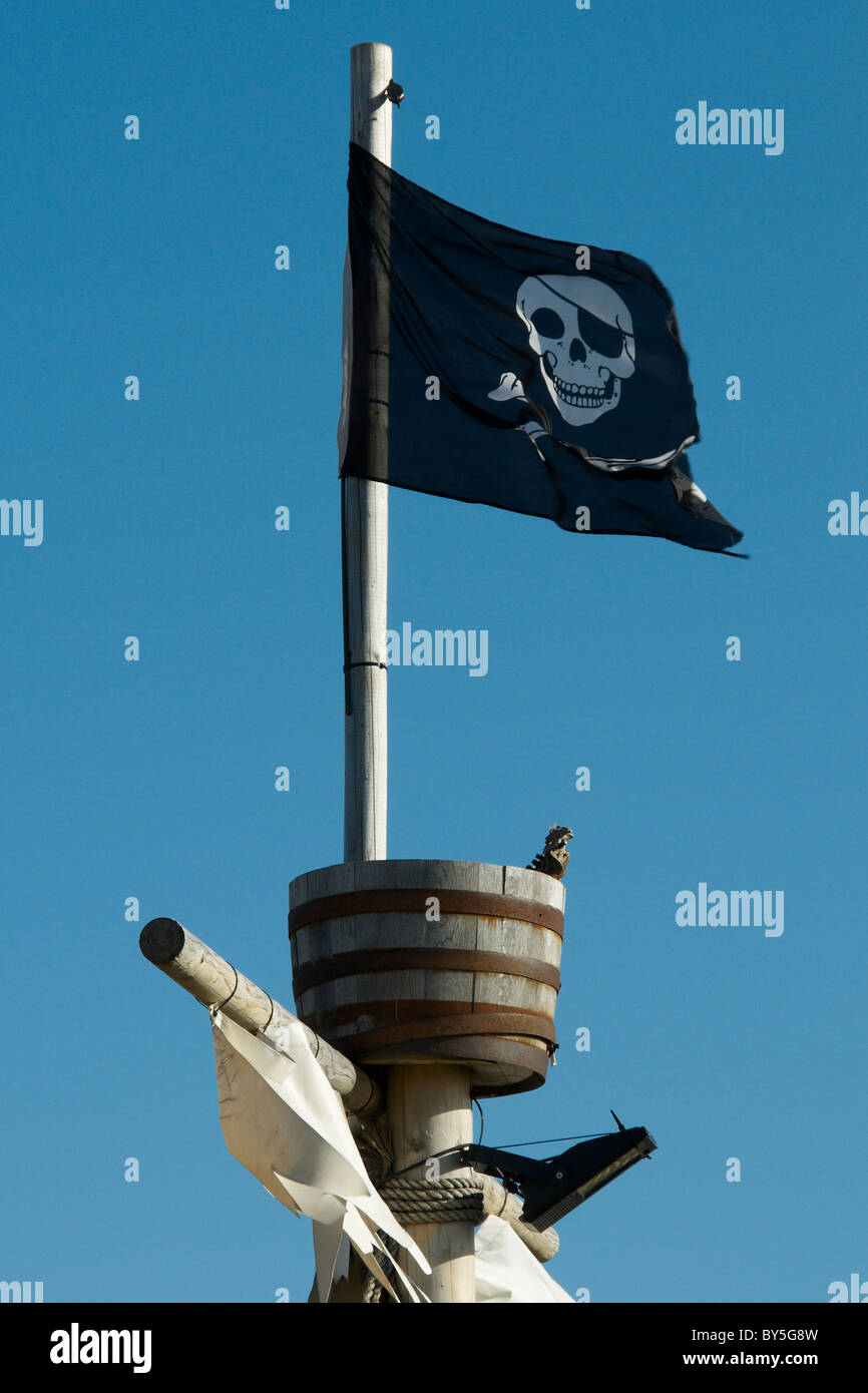Piratenflagge Jolly Roger auf einem Mast mit einem Crows nest Stockfoto