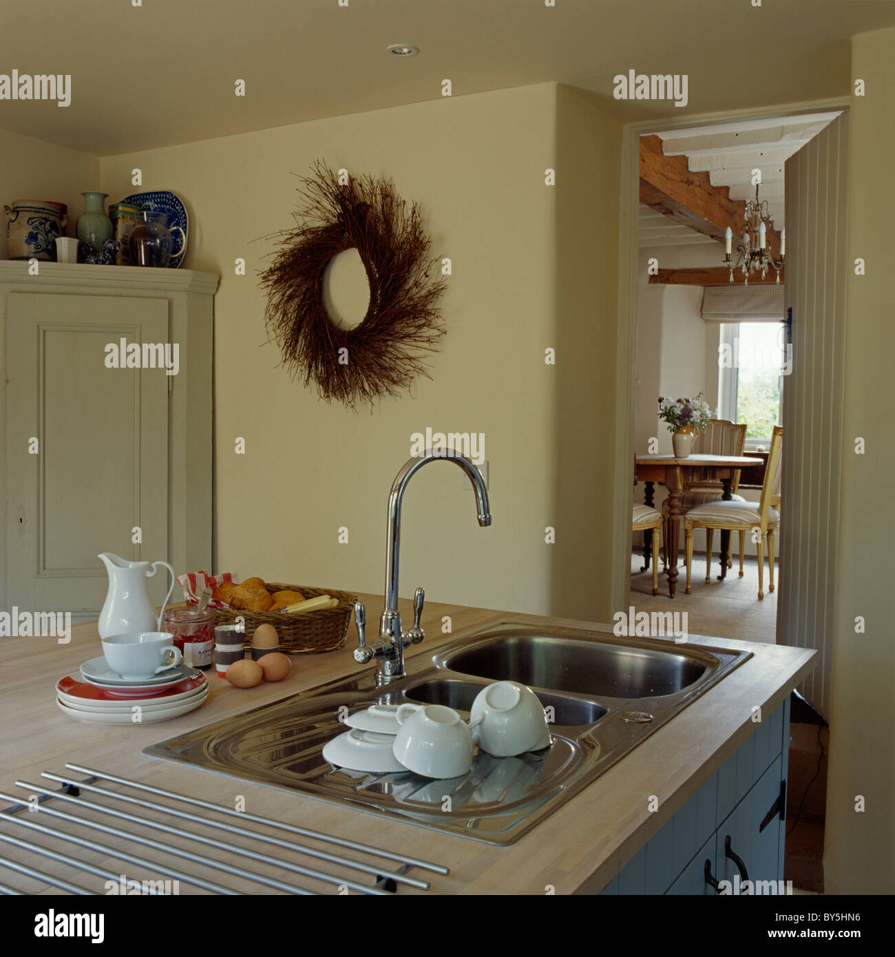 Weißes Geschirr auf Abtropffläche Edelstahl-Spüle mit Mischbatterie in  Creme Cottage-Küche mit rustikalen Kranz an der Wand Stockfotografie - Alamy