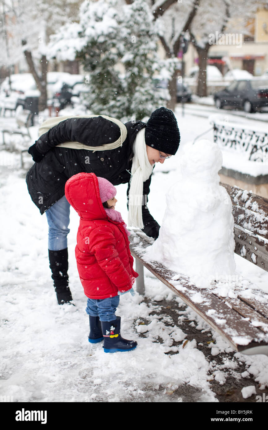 Eine Frau und Kind einen Schneemann bauen, auf einer Bank in Toledo, Spanien. Stockfoto
