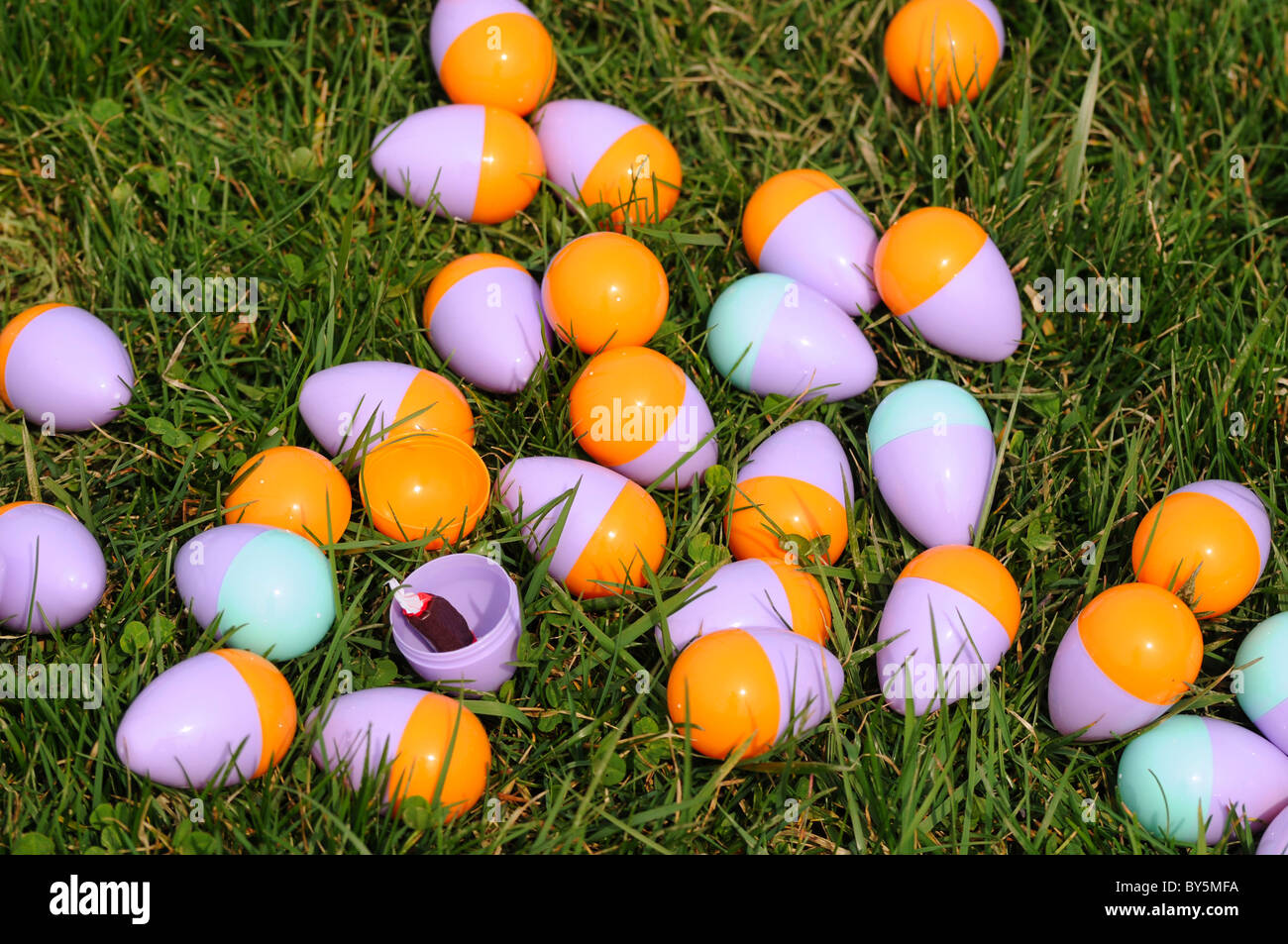 Ein Cluster von farbigen Ostereier auf einer Wiese mit einem geöffnet, um die Süßigkeiten im Inneren zeigen Stockfoto