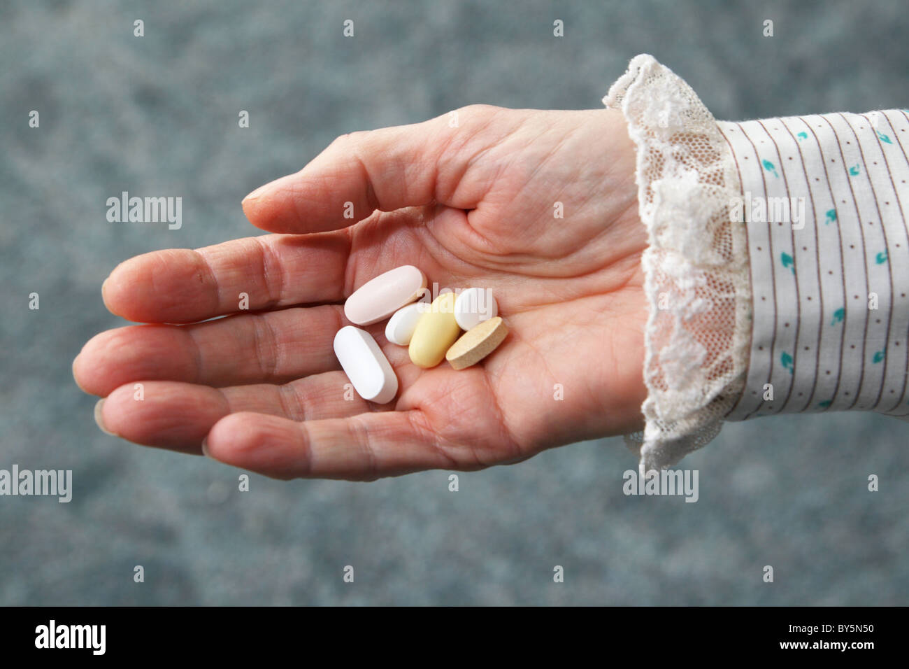 eine alte Frau Hand hält sechs Tabletten in der Handfläche Stockfoto