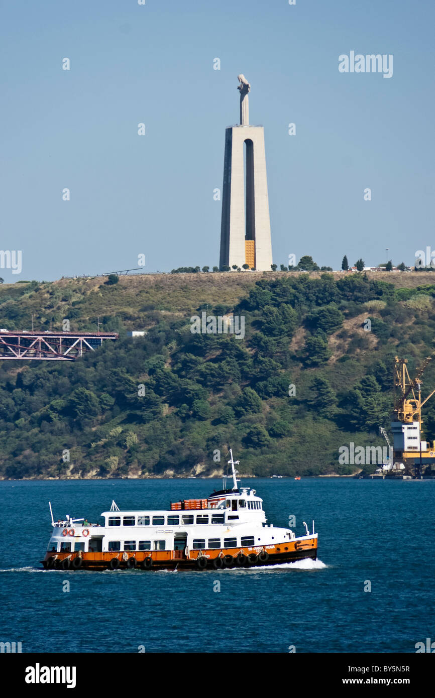 Transtejo e eine Soflusa Fähre Trafaria Praia auf Tejo von Tagus River Bridge (Brücke 25 de Abril) mit Cristo-Rei hinter Stockfoto