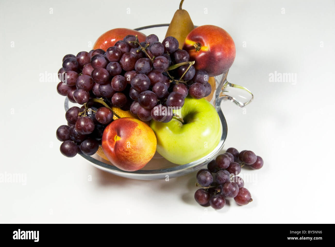 Stock Foto von Obstschale mit Trauben, Äpfel, Orangen und eine Birne gefüllt. Die Schüssel ist Apfel geformt. Stockfoto