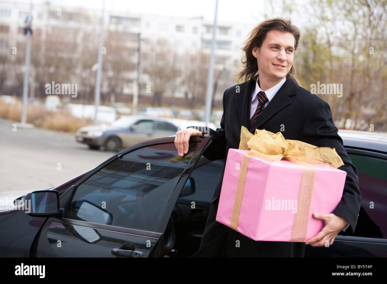 Porträt von glücklich Geschäftsmann aus seinem Auto mit großen Geschenkbox in hand gehen Stockfoto