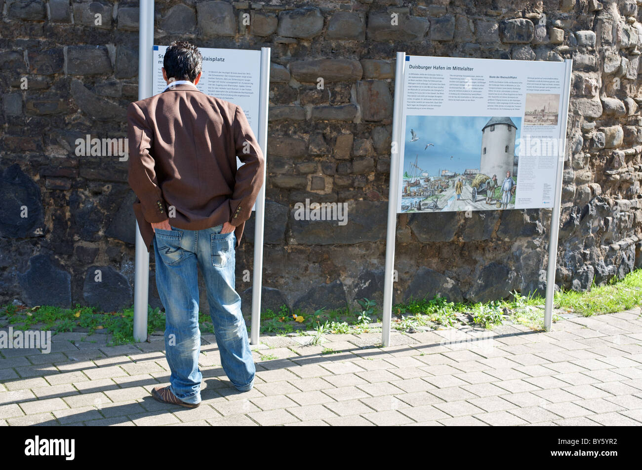 Mann sucht bei touristischen Infotafel, Duisburg, Deutschland. Stockfoto