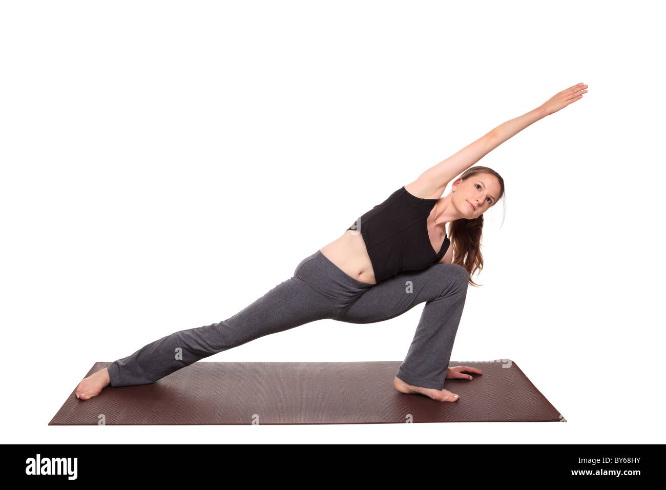 Studioaufnahme einer Fit kaukasischen Frau hält die Parsvakonasana Seite Winkel stellen Yogaposition auf eine Gymnastikmatte isoliert. Stockfoto