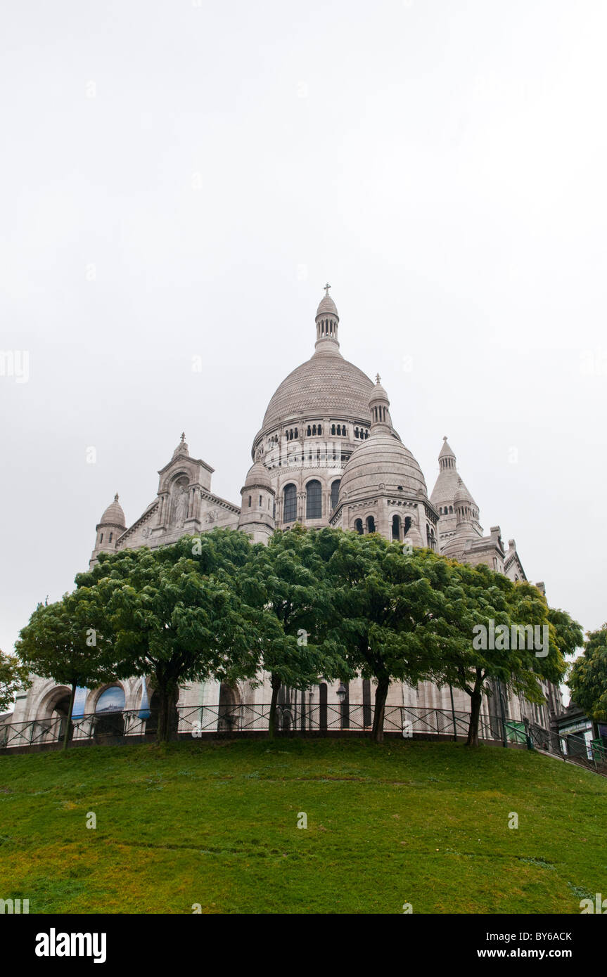 Basilika Sacré-Cœur Weiße Kuppeln auf dem Montmartre-Hügel Paris Frankreich // PARIS, Frankreich — die Basilika Sacré-Cœur auf dem Montmartre-Hügel ist ein bedeutendes religiöses und kulturelles Wahrzeichen in Paris. Diese berühmte Basilika mit weißer Kuppel, die 1914 fertiggestellt wurde, ist für ihren römisch-byzantinischen Architekturstil bekannt und aus Château-Landon-Stein gebaut, der im Laufe der Zeit bleicht und härtet. Es liegt auf dem höchsten Punkt von Paris und bietet einen Panoramablick auf die Stadt. Die unverwechselbare Architektur und die ruhige Inneneinrichtung der Basilika ziehen Besucher aus der ganzen Welt an. Stockfoto