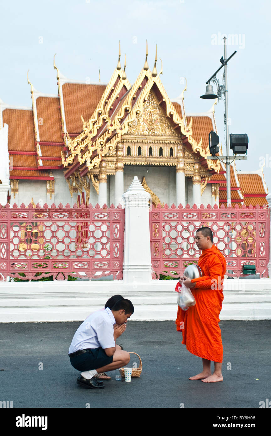 Zwei Menschen vor einem Mönch zu beten, nachdem sie, Himalms vor Wat Benjamabophit, Bangkok, Thailand gegeben hatte Stockfoto