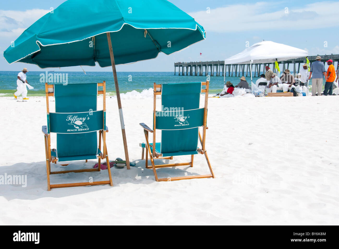 Touristischen Strandstühle mit BP-Öl-Arbeiter in Ferne Stockfoto