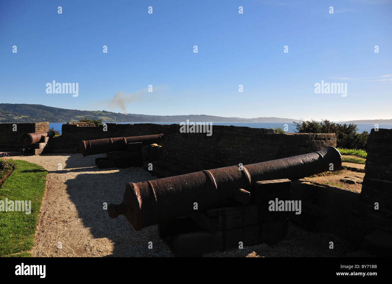 Blauer Himmelsblick auf Rost Eisen Kanonen Winkel von Bombern in der niedrigen zugewandten Wand des Fort San Antonio, Ancud, Chiloé Insel, Chile Stockfoto